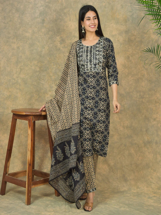 Woman wearing a patterned kurta with a matching dupatta against a textured brown background