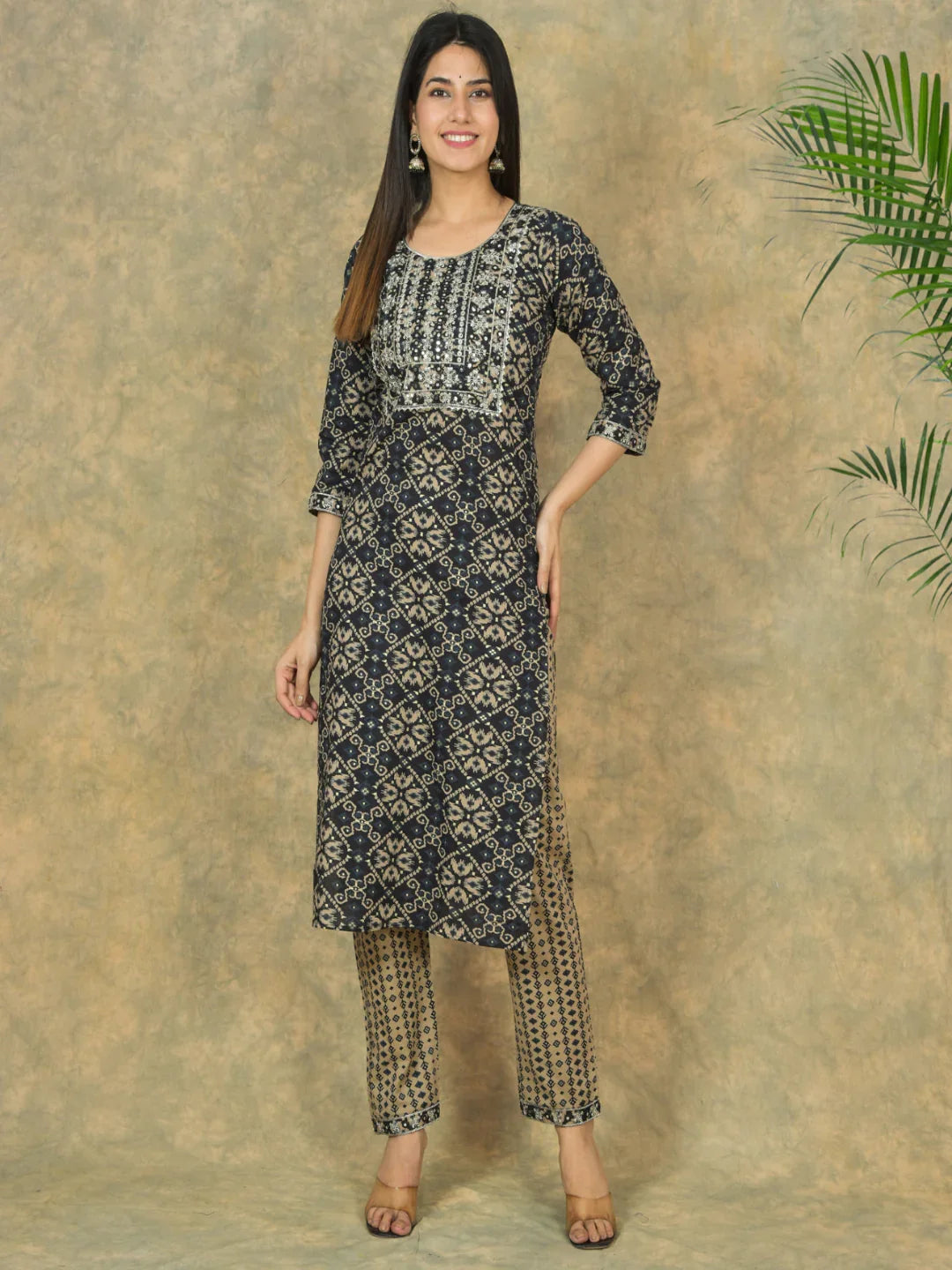 Woman wearing a black and white patterned kurta with matching pants against a beige background.