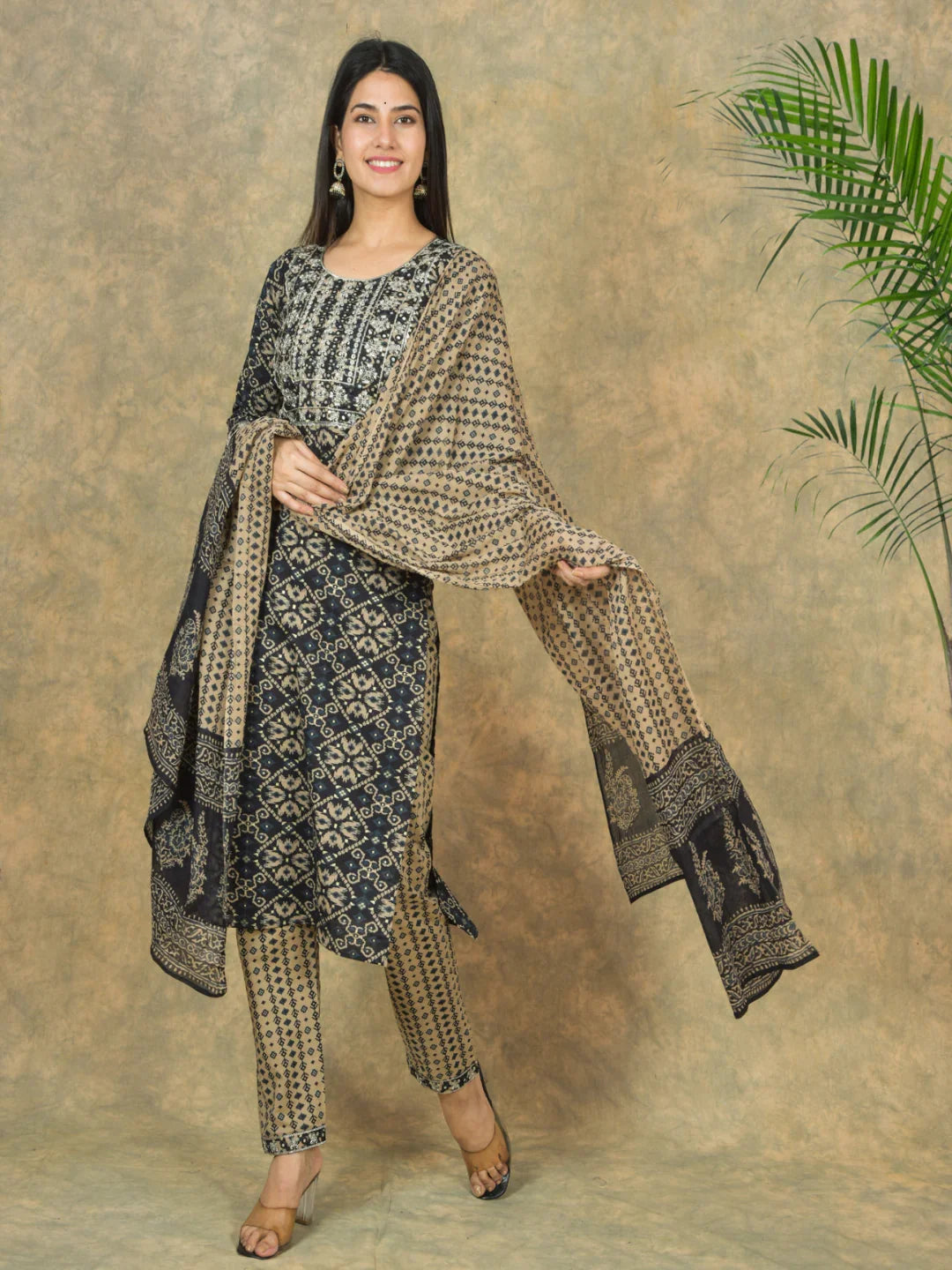 Woman wearing a traditional outfit with a patterned shawl against a textured wall.