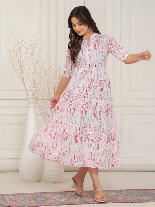 Woman wearing a white dress with red patterns in a minimal indoor setting