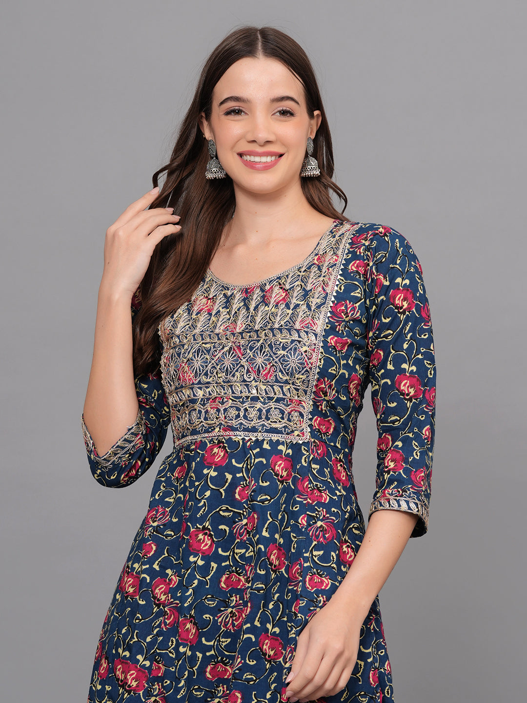 Woman wearing a floral and embroidered dress on a gray background