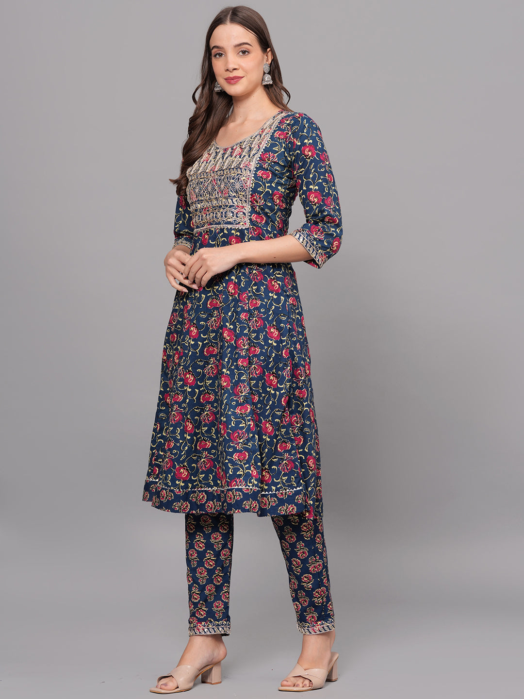 Woman wearing a navy blue floral dress with red flowers on a gray background