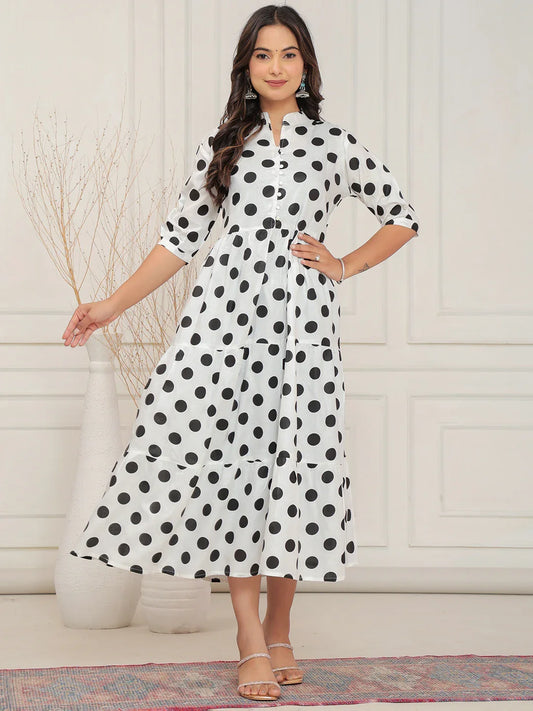 Woman wearing a white dress with black polka dots in a minimalistic setting