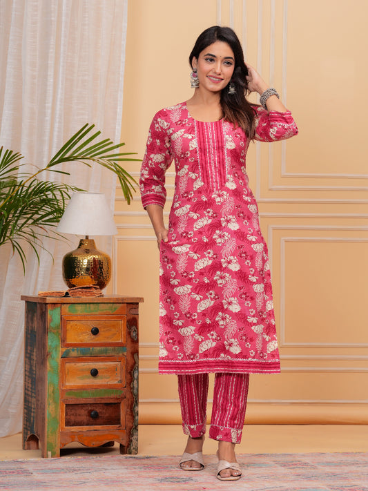 Woman wearing a pink floral kurta with pants in a room setting.