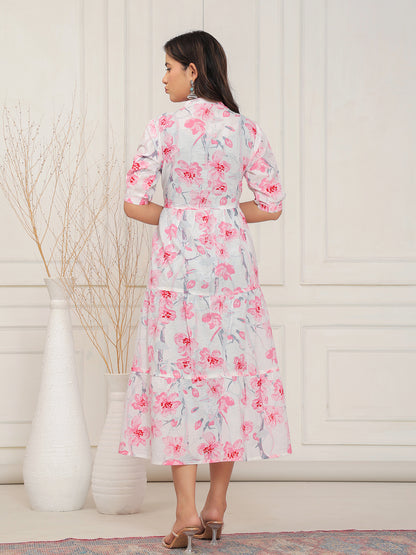 Woman wearing a floral dress standing in a room with a white wall and decorative elements.