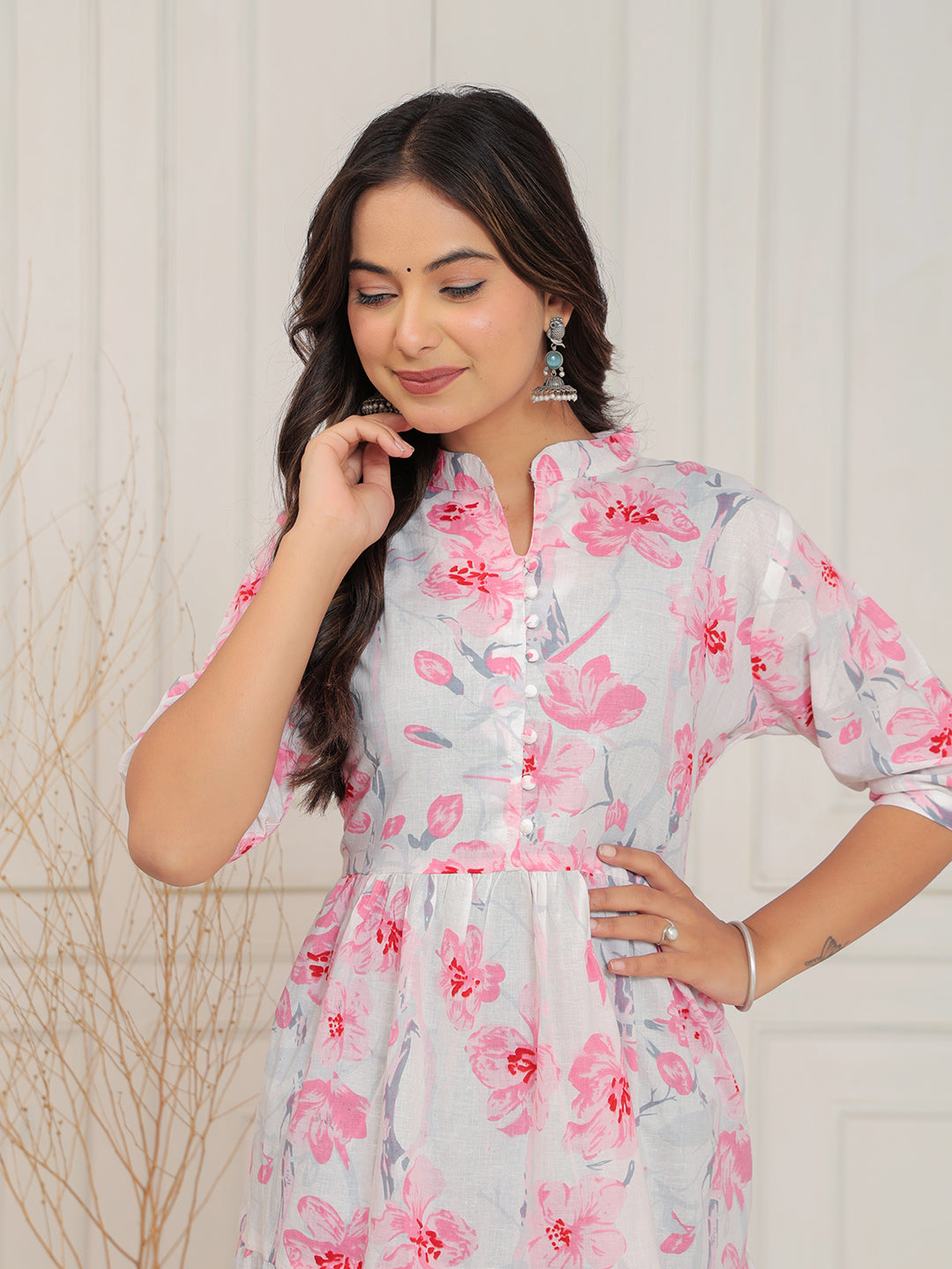 Woman wearing a floral dress with pink and white flowers against a neutral background