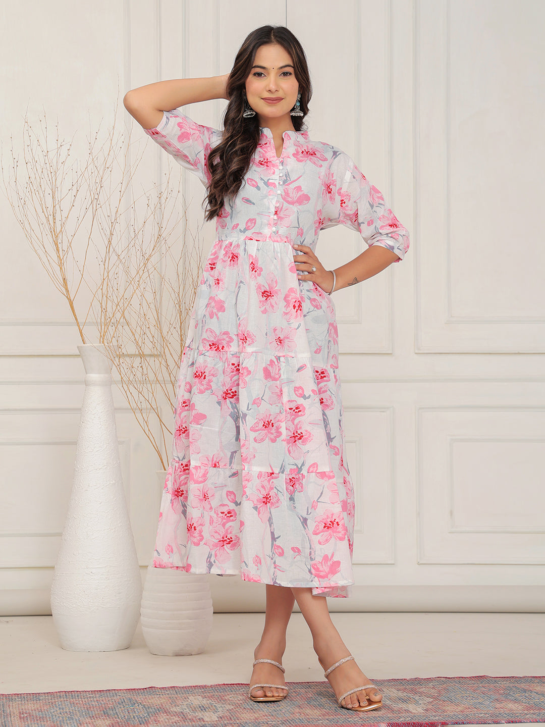 Woman wearing a floral dress standing in a room with decorative elements.