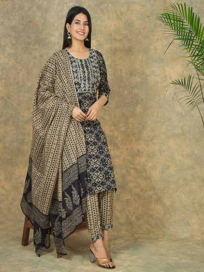 Woman wearing a traditional outfit with a patterned shawl against a textured wall. > Mitrika