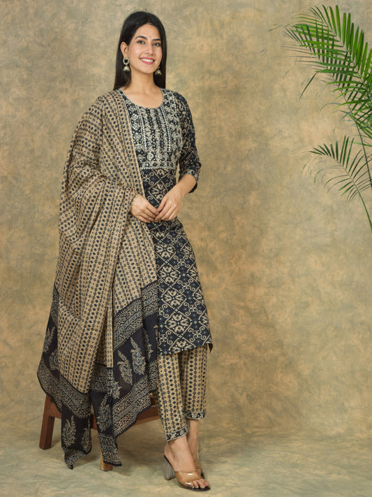 Woman wearing a traditional outfit with a patterned shawl against a textured wall. > Mitrika