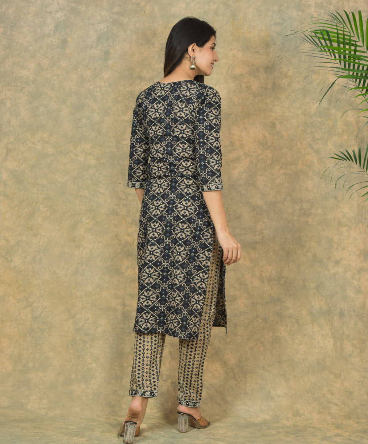 Woman wearing a black and white patterned kurta with pants against a beige background