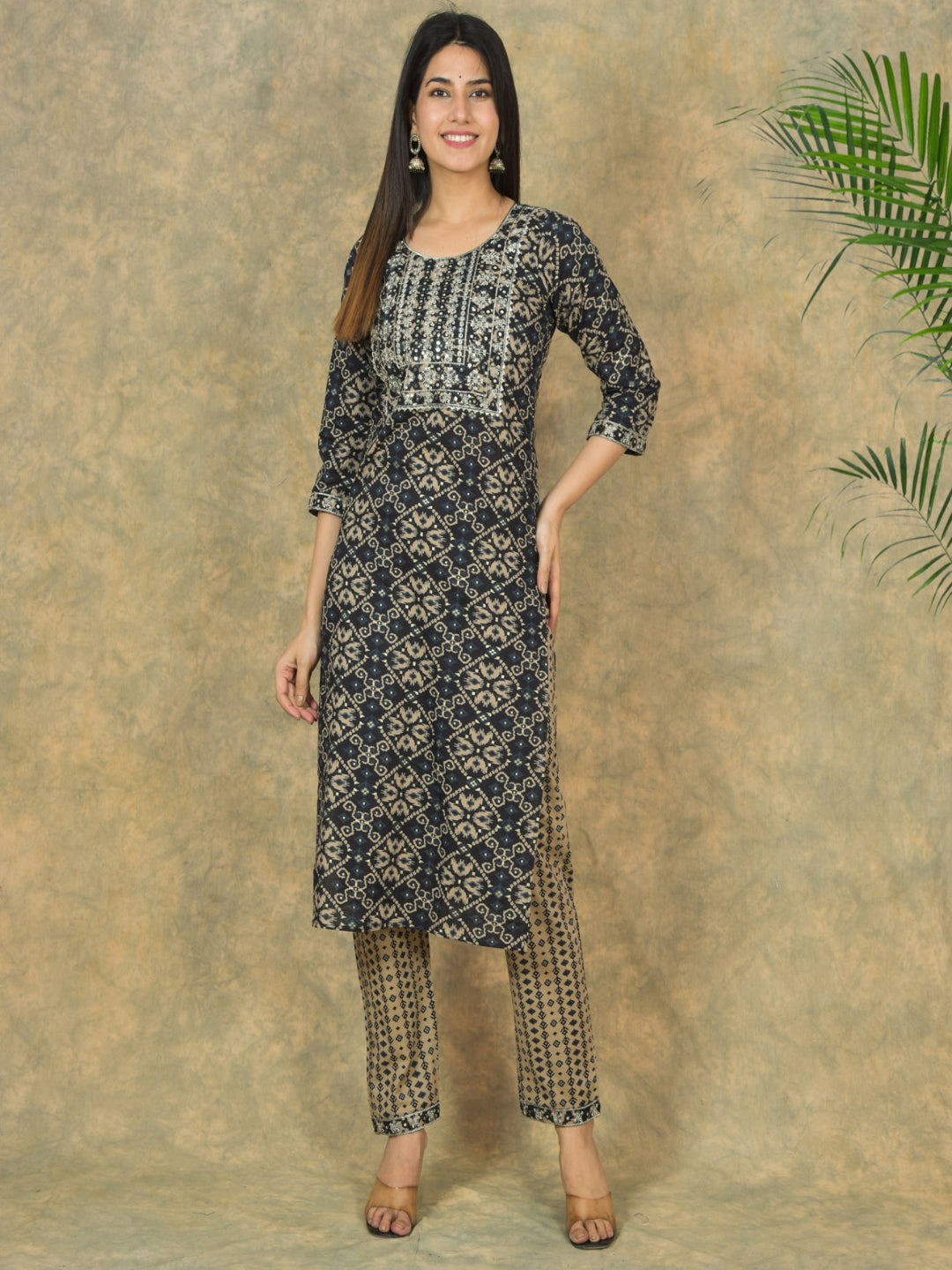 Woman wearing a black and white patterned kurta with matching pants against a beige background.