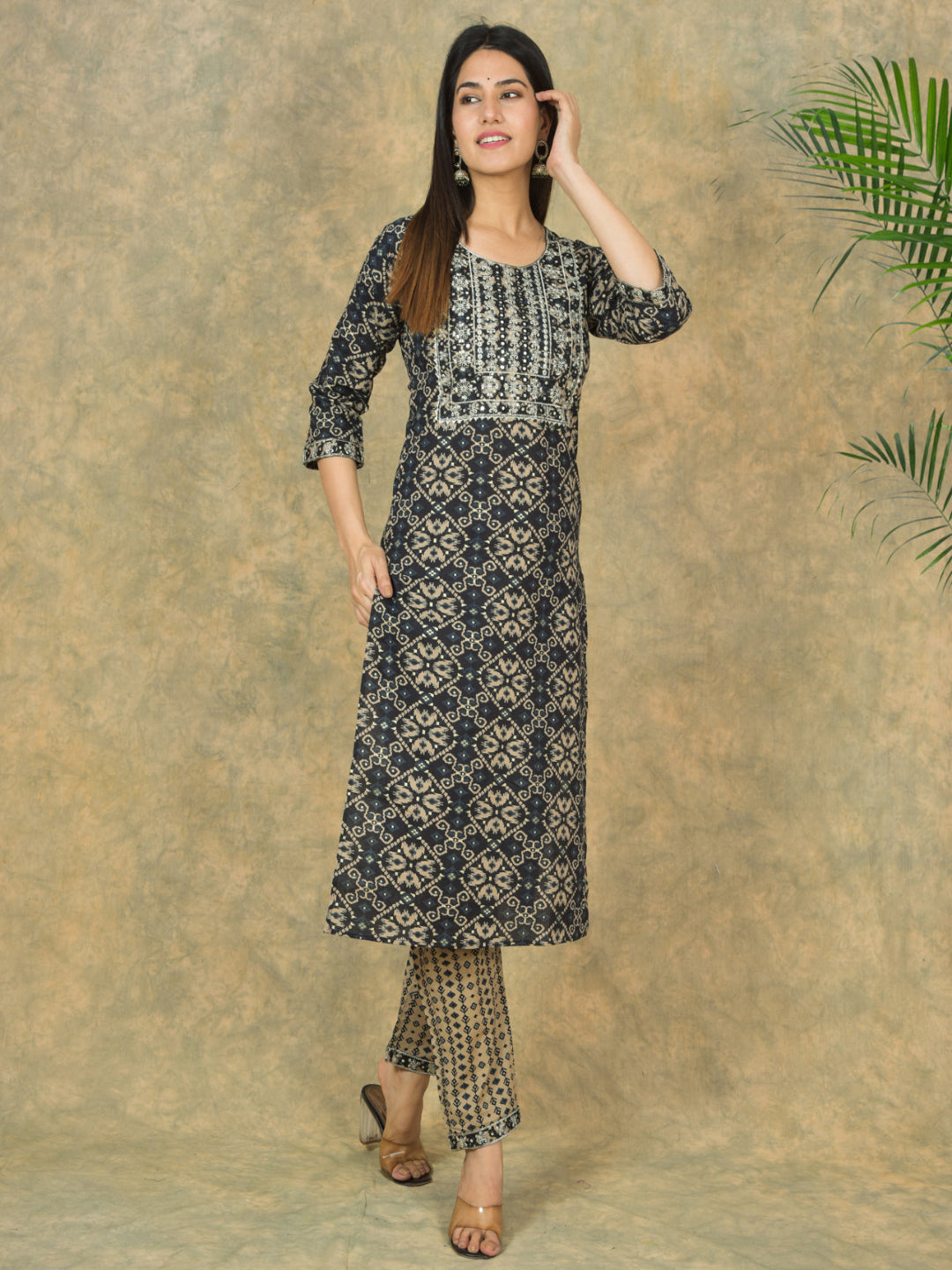 Woman wearing a black and white patterned kurta with palazzo pants against a beige background.