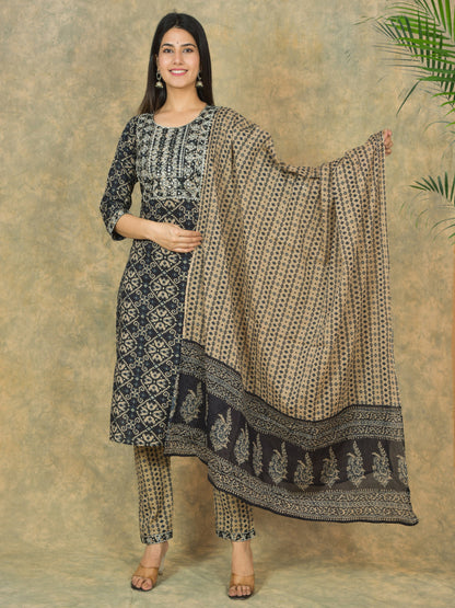 Woman holding a patterned dupatta against a textured wall