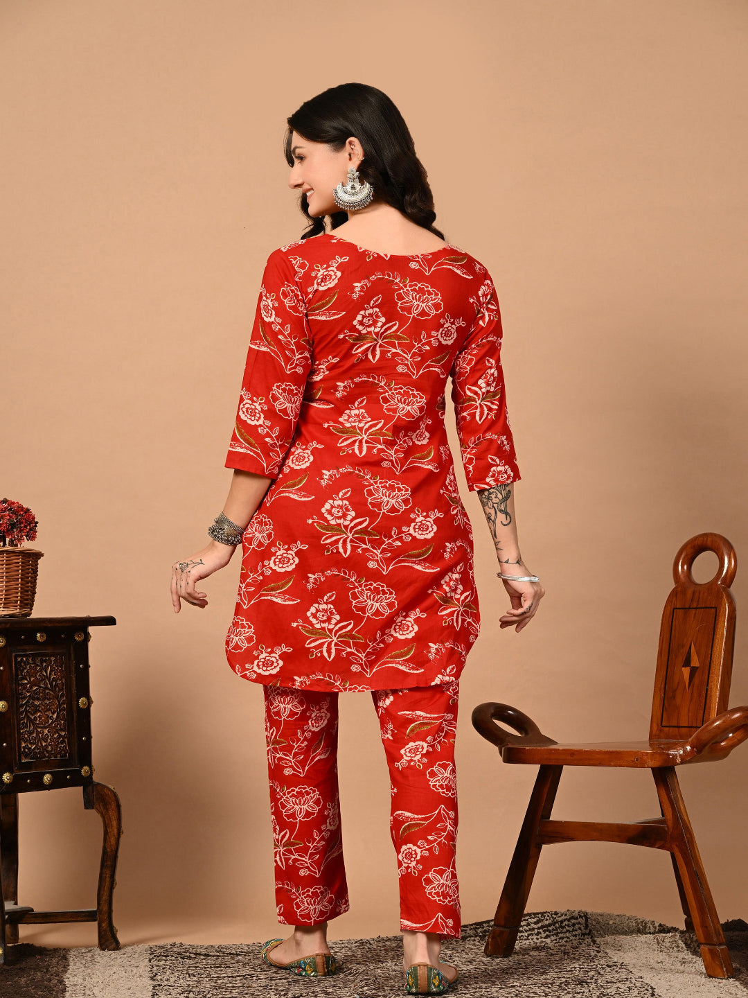 Woman wearing a red floral outfit standing against a beige background