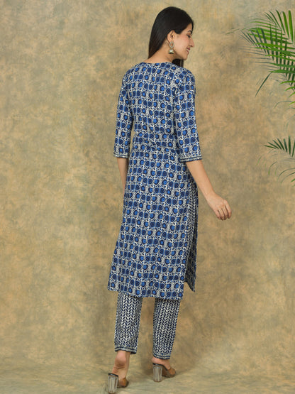 Woman wearing a blue and white patterned kurta with pants against a textured beige background.