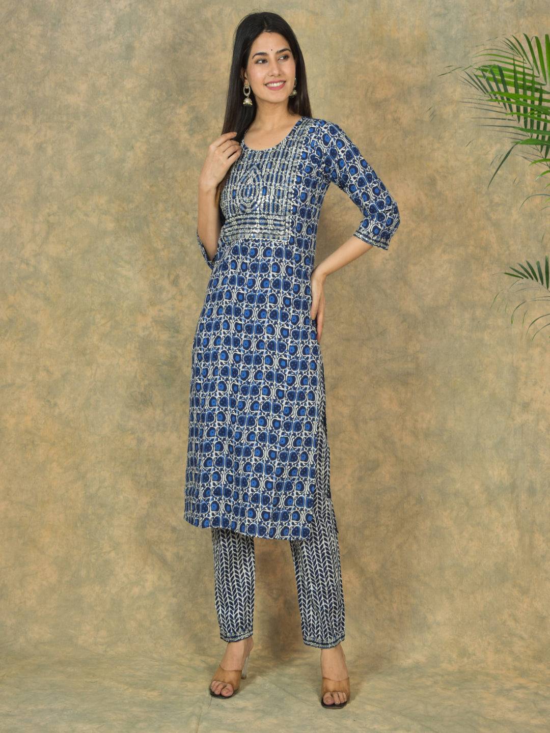 Woman wearing a blue patterned kurta with pants against a textured beige background