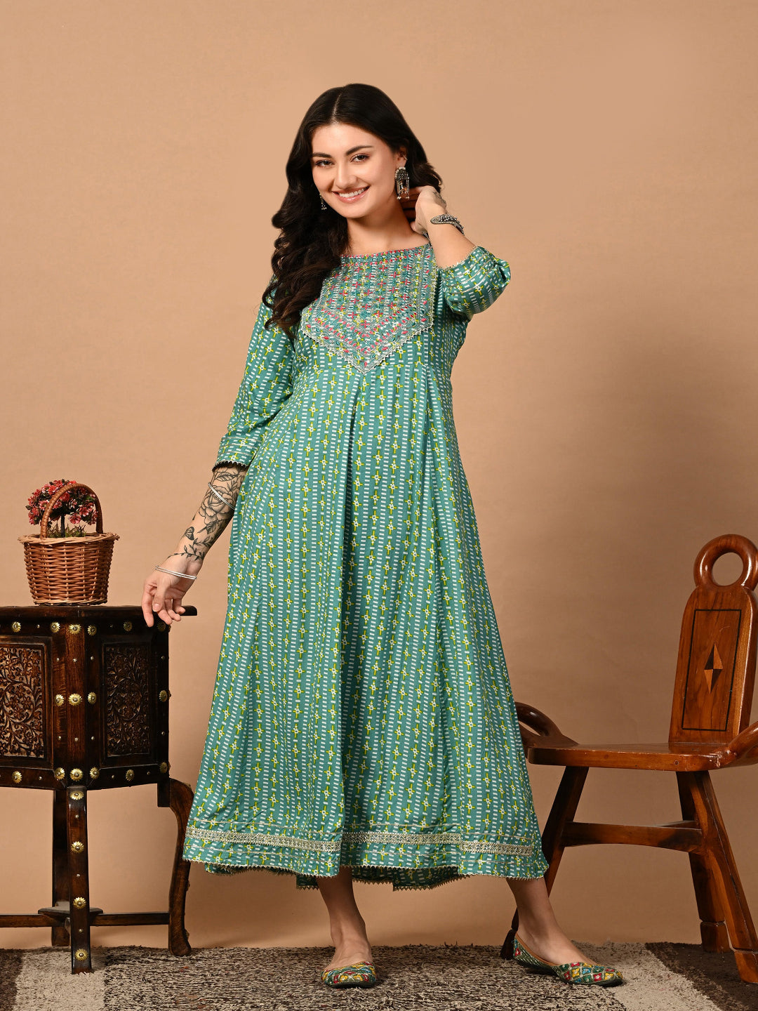 Woman wearing a green patterned kurta standing against a beige background