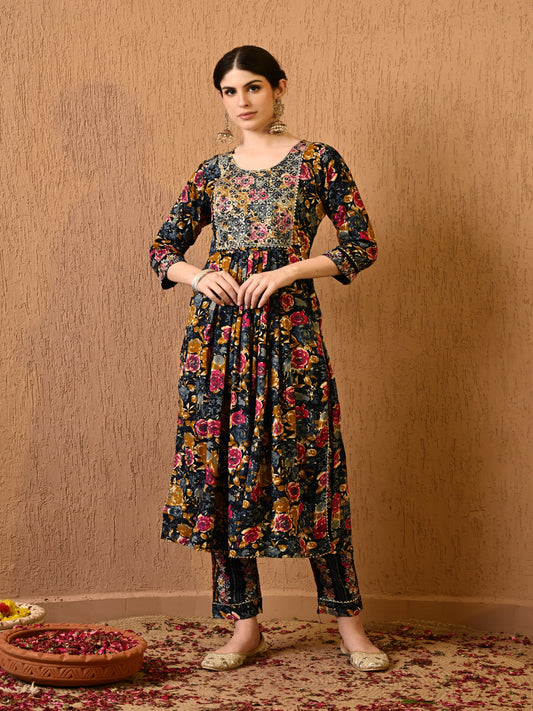 Woman wearing a floral dress and pants against a beige wall. > Mitrika