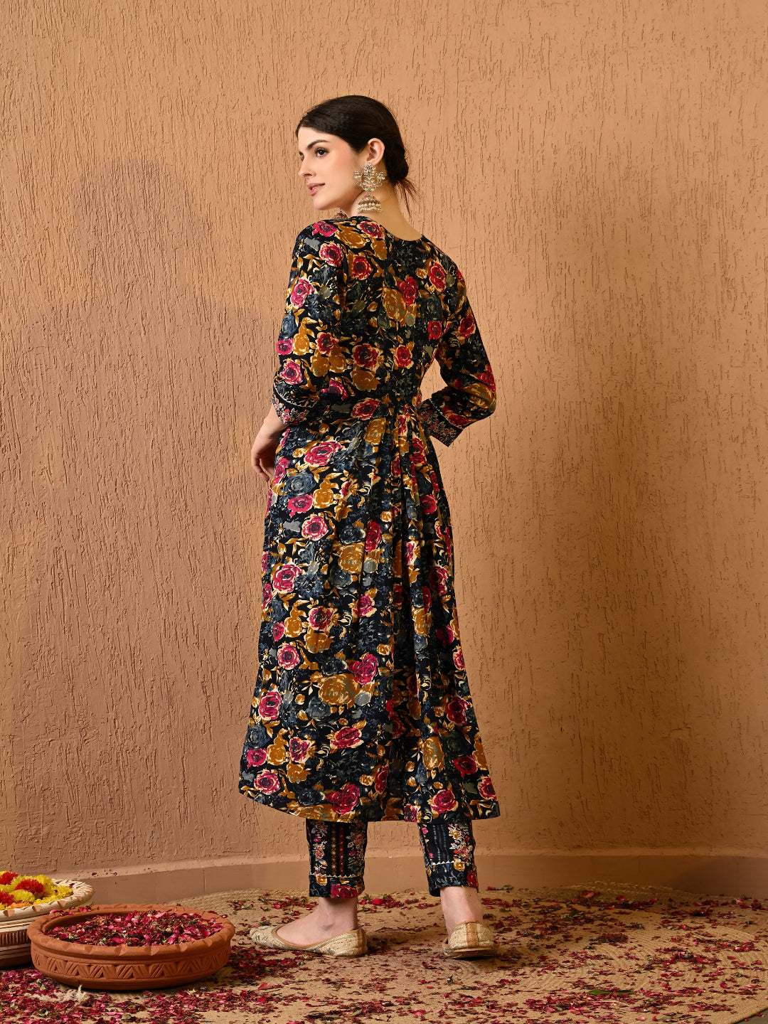 Woman wearing a floral dress standing against a beige wall.