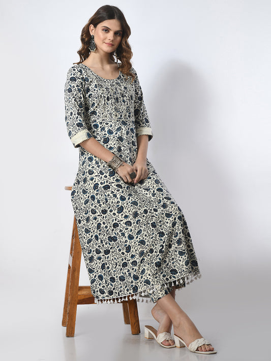 Woman wearing a floral dress sitting on a wooden stool against a white background