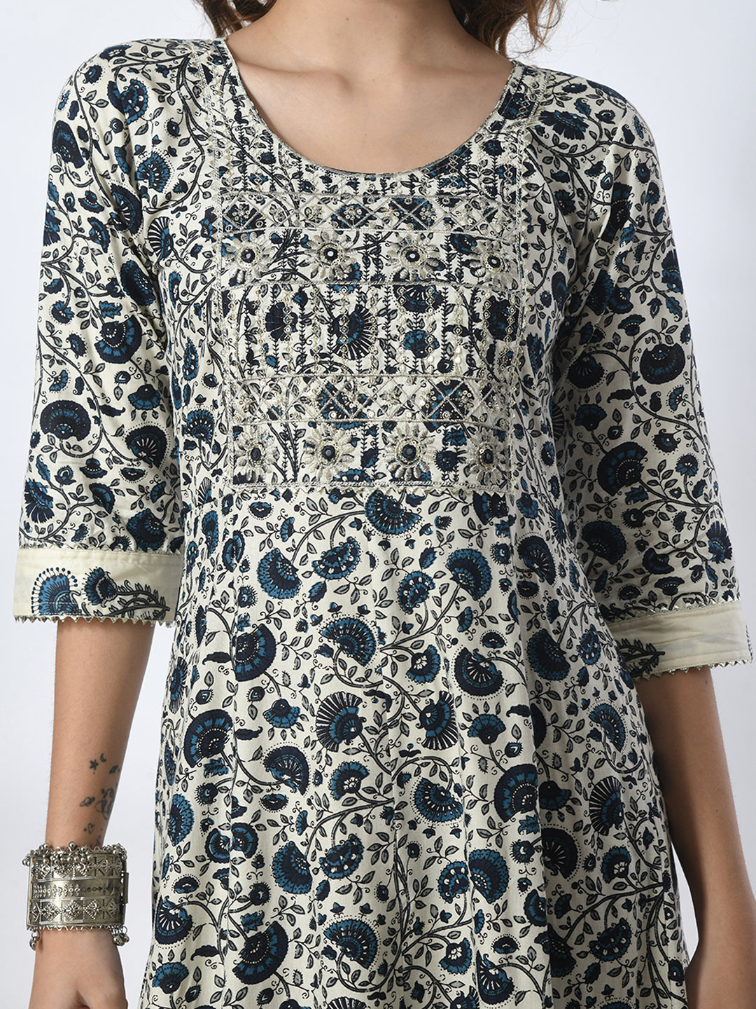 Woman wearing a patterned dress with blue and black design on a white background