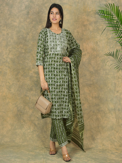 Woman wearing a green patterned outfit with a beige handbag against a textured brown background