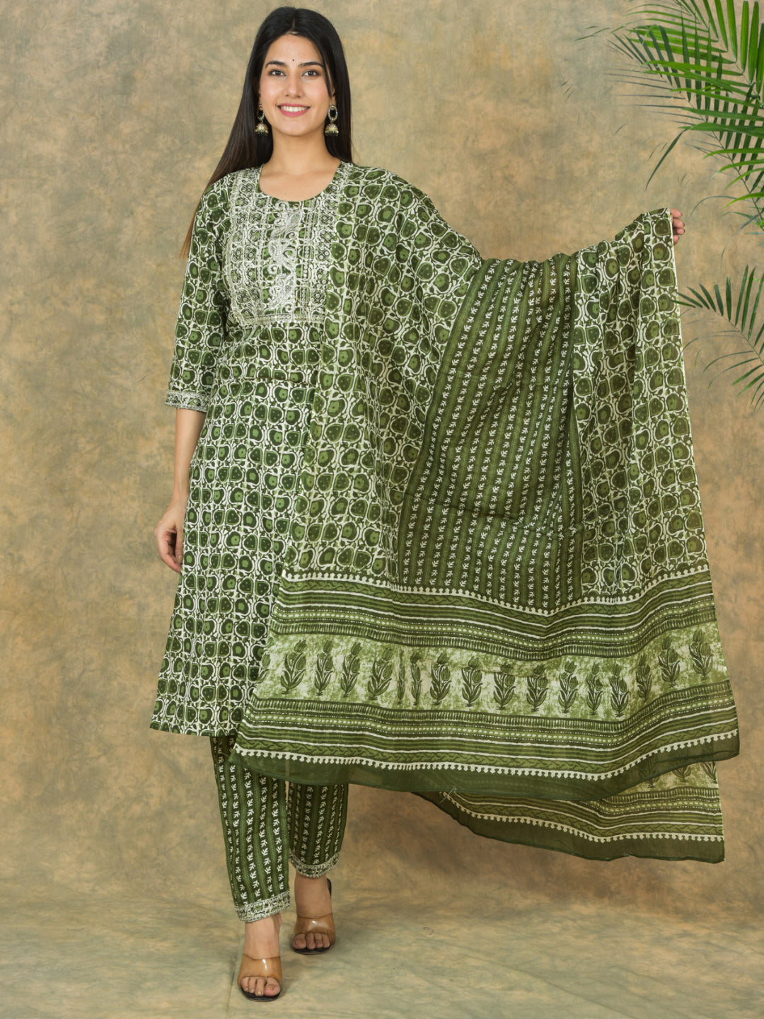Woman wearing a green and white patterned traditional outfit against a brown background