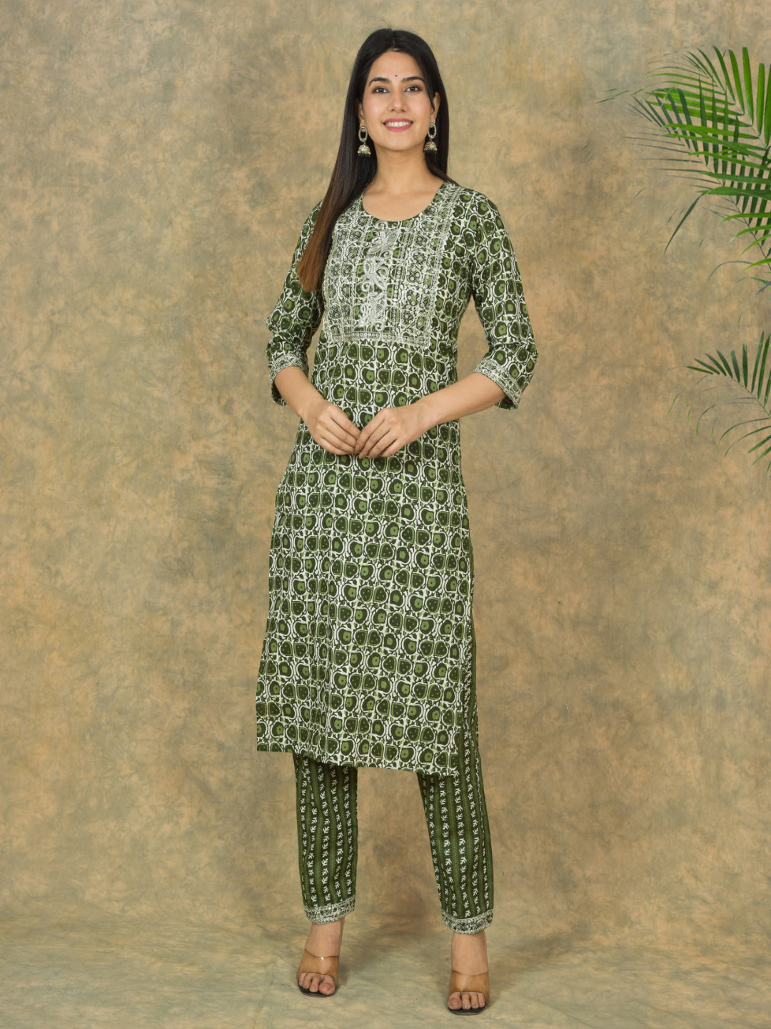 Woman wearing a green patterned kurta with pants against a brown background