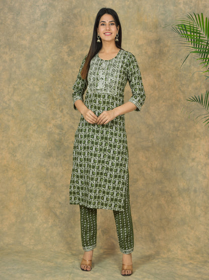 Woman wearing a green patterned kurta with pants against a brown background