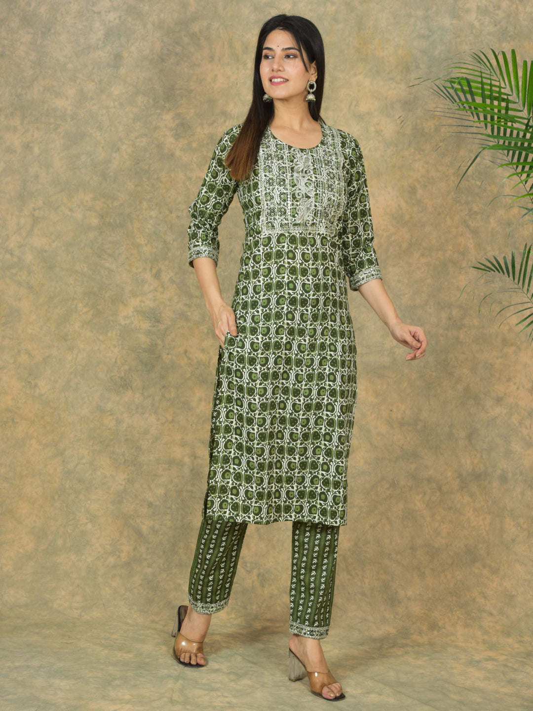 Woman wearing a green and white patterned kurta with pants against a brown background