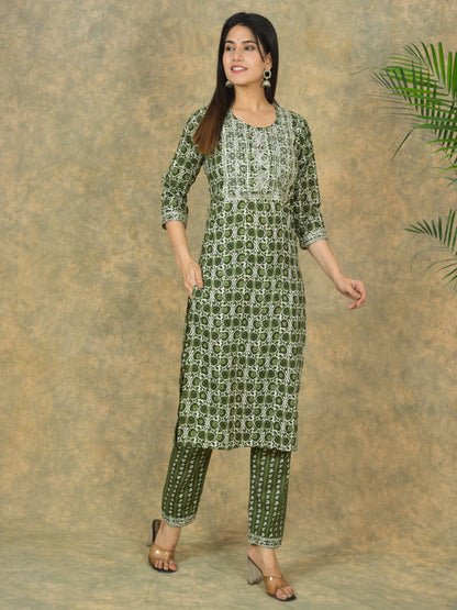 Woman wearing a green and white patterned kurta with pants against a brown background