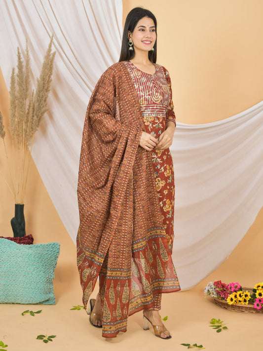 Woman wearing a traditional brown patterned outfit with a white draped fabric background