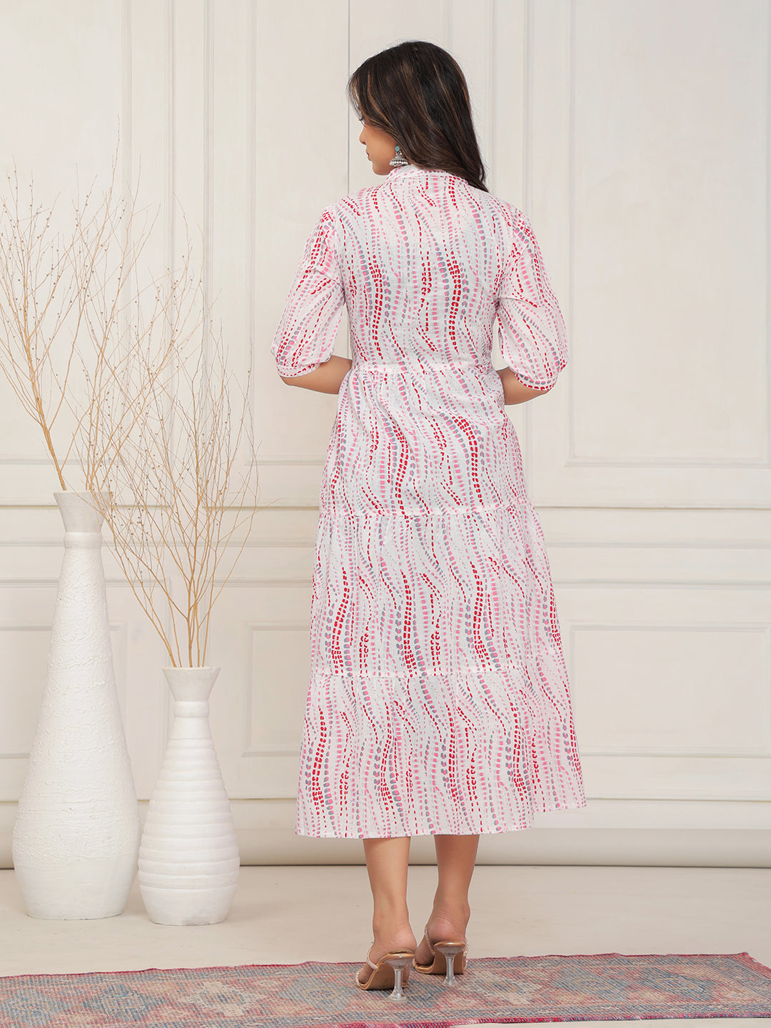 Woman wearing a white dress with red patterns in a minimal indoor setting