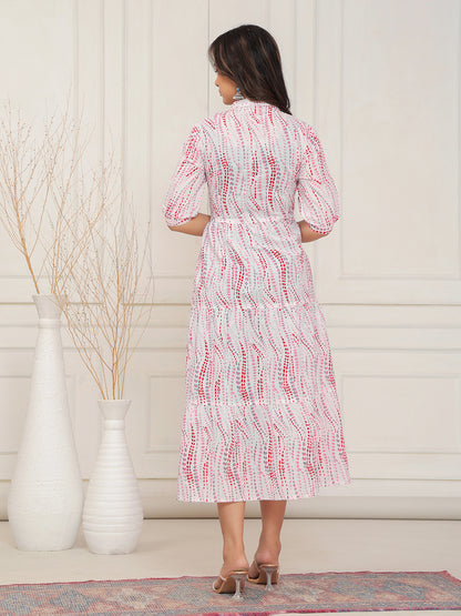 Woman wearing a white dress with red patterns in a minimal indoor setting