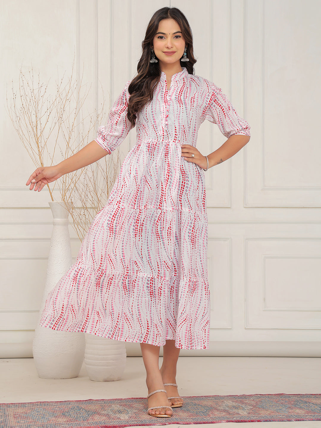 Woman wearing a red and white patterned dress standing against a white wall.