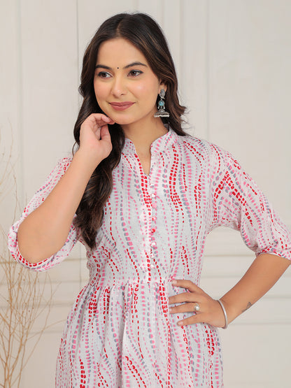 Woman wearing a white and red patterned dress against a plain background