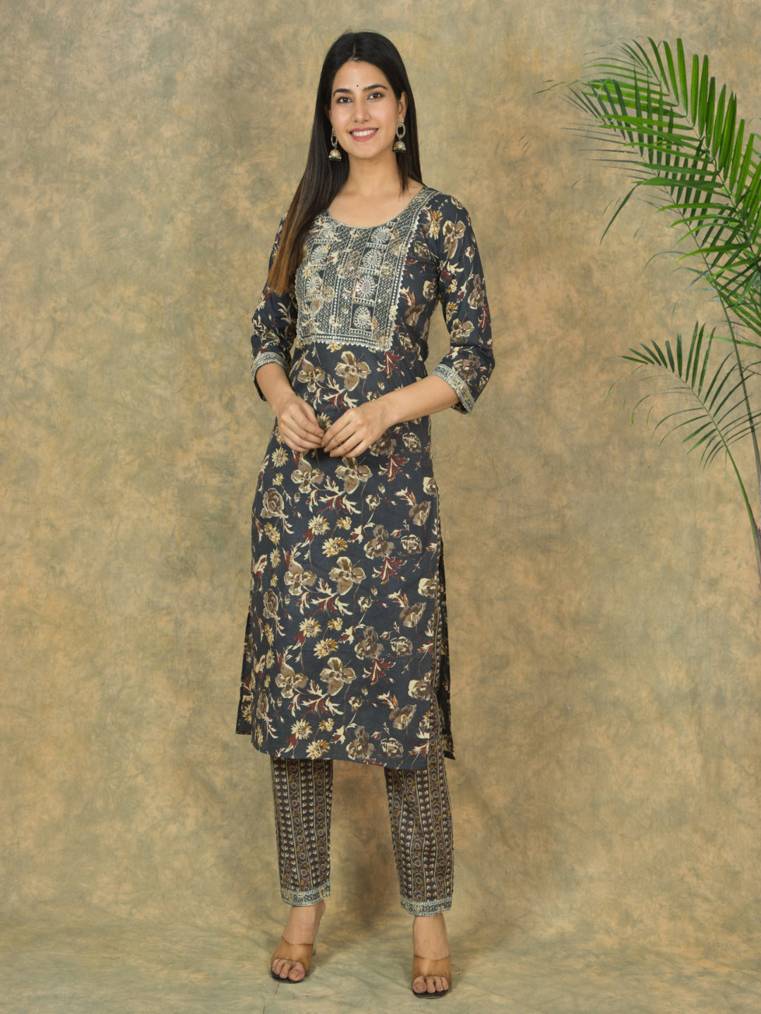 Woman wearing a floral kurta with pants against a textured brown background