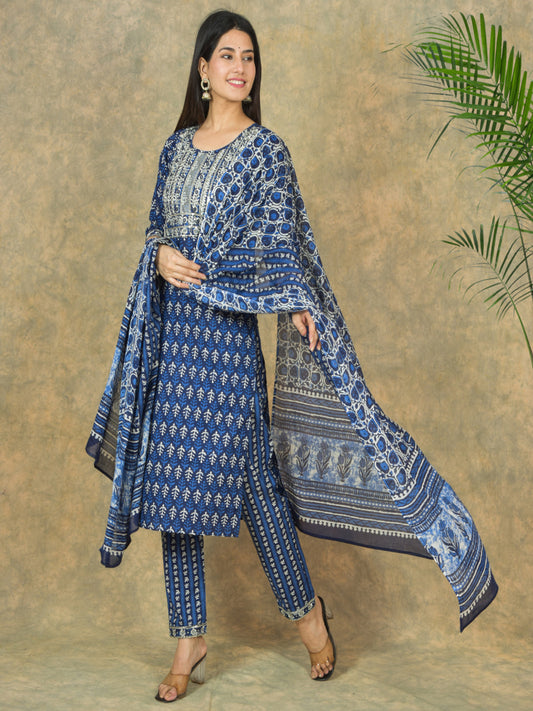 Woman wearing a blue patterned outfit with a matching dupatta against a beige background