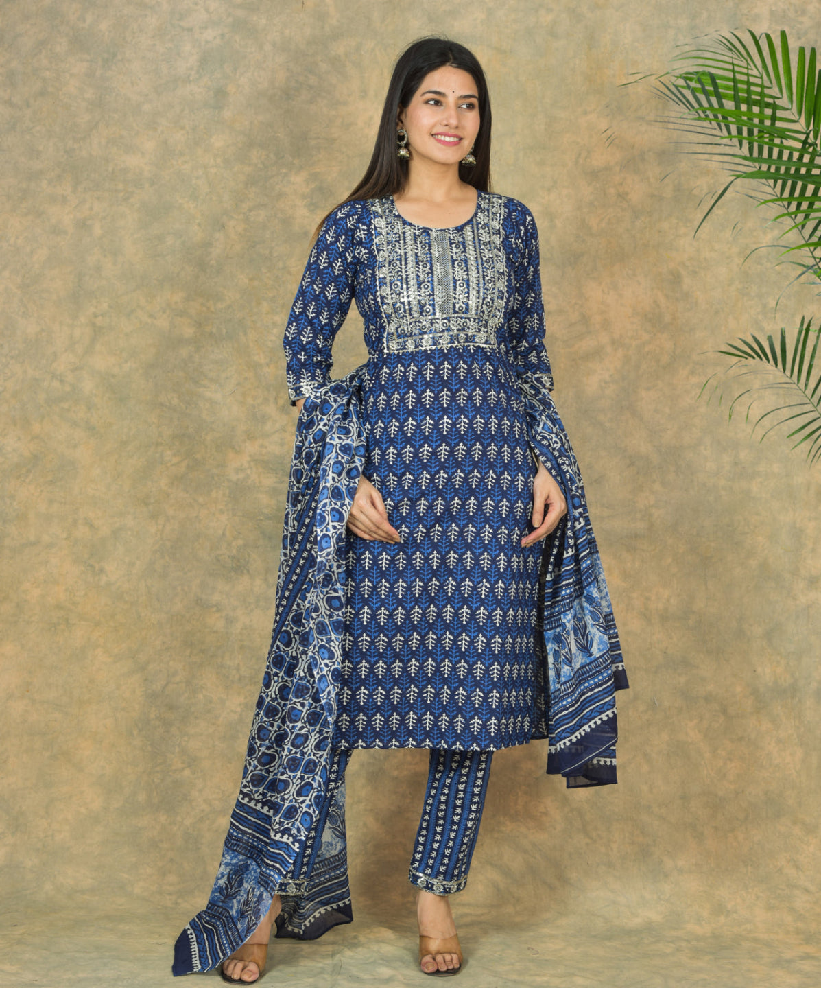 Woman wearing a blue patterned outfit against a textured beige background