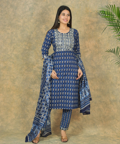 Woman wearing a blue patterned outfit against a textured beige background