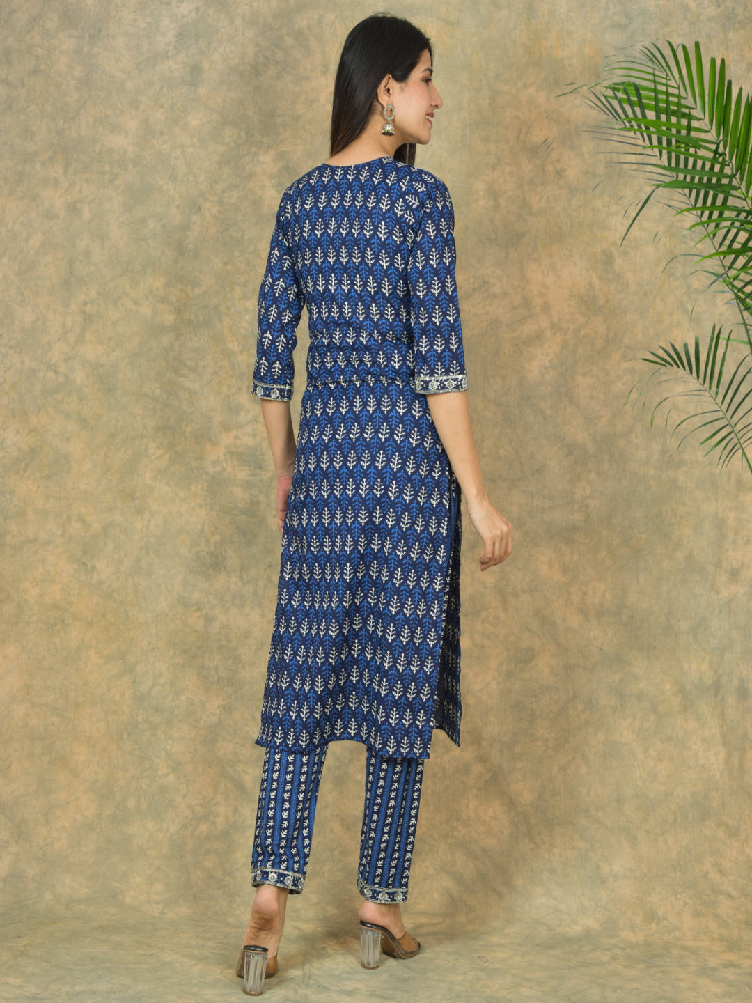 Woman wearing a blue patterned kurta with pants against a textured beige background