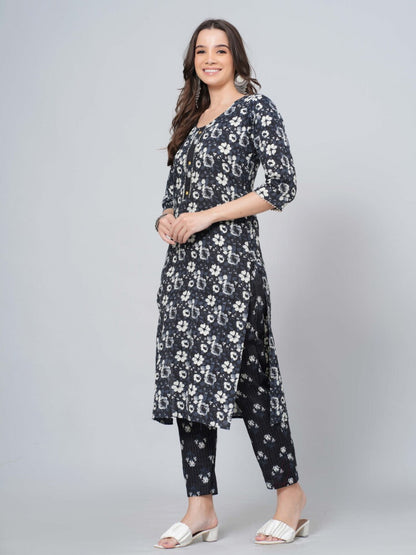 Woman wearing a navy floral dress and pants on a gray background