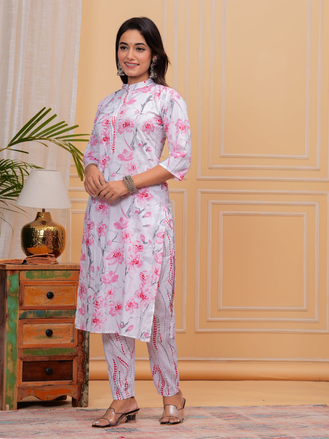 Woman wearing a floral kurta with a wooden side table and lamp in the background