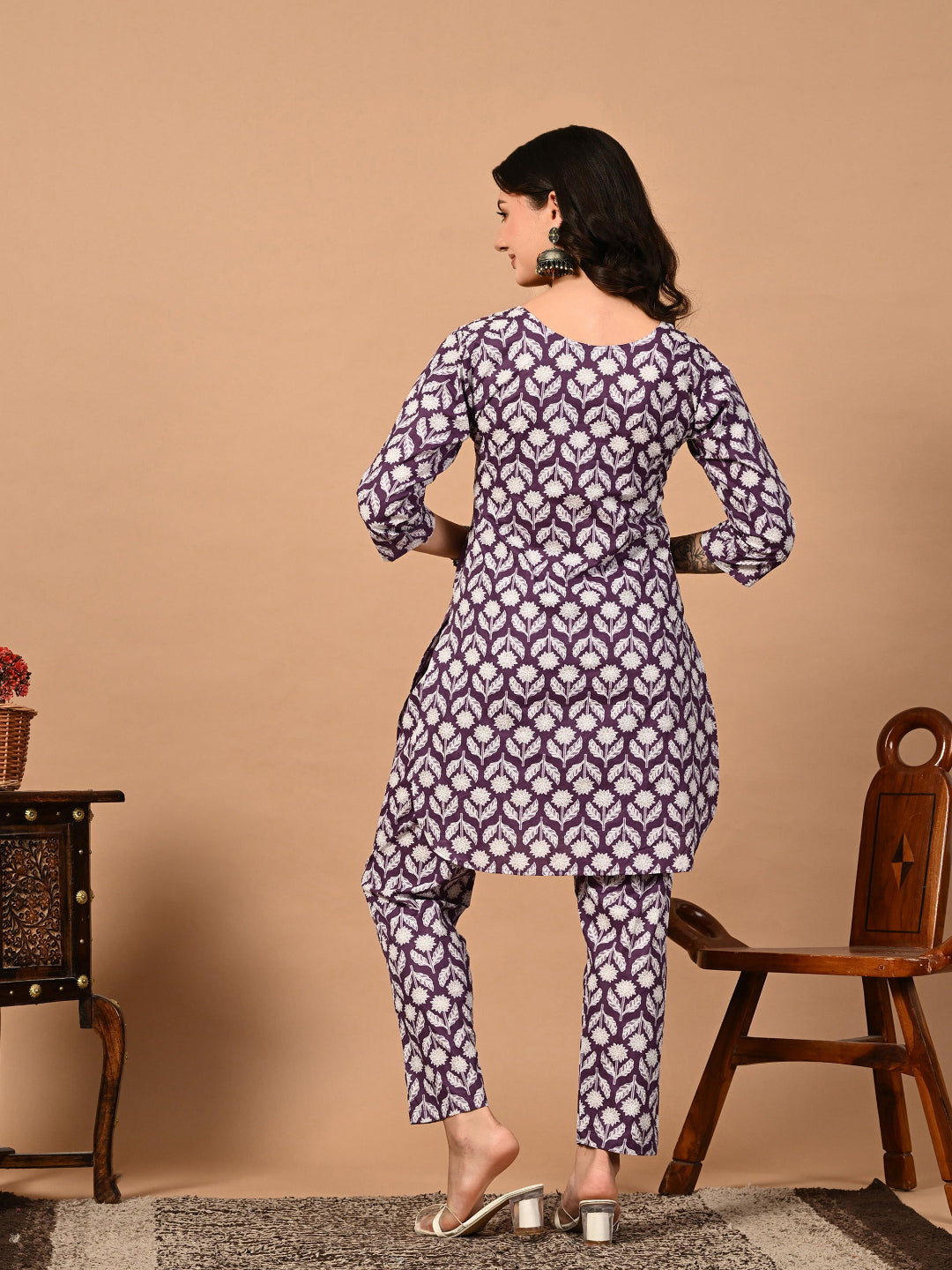 Woman wearing a purple and white patterned kurta with pants on a beige background