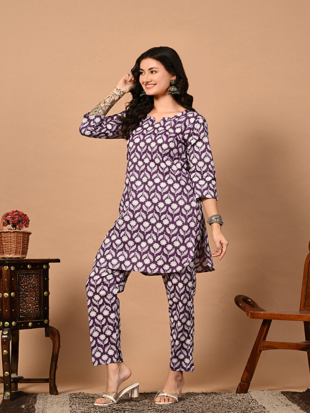 Woman wearing a purple patterned outfit against a beige background