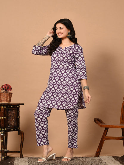 Woman wearing a purple patterned outfit against a beige background