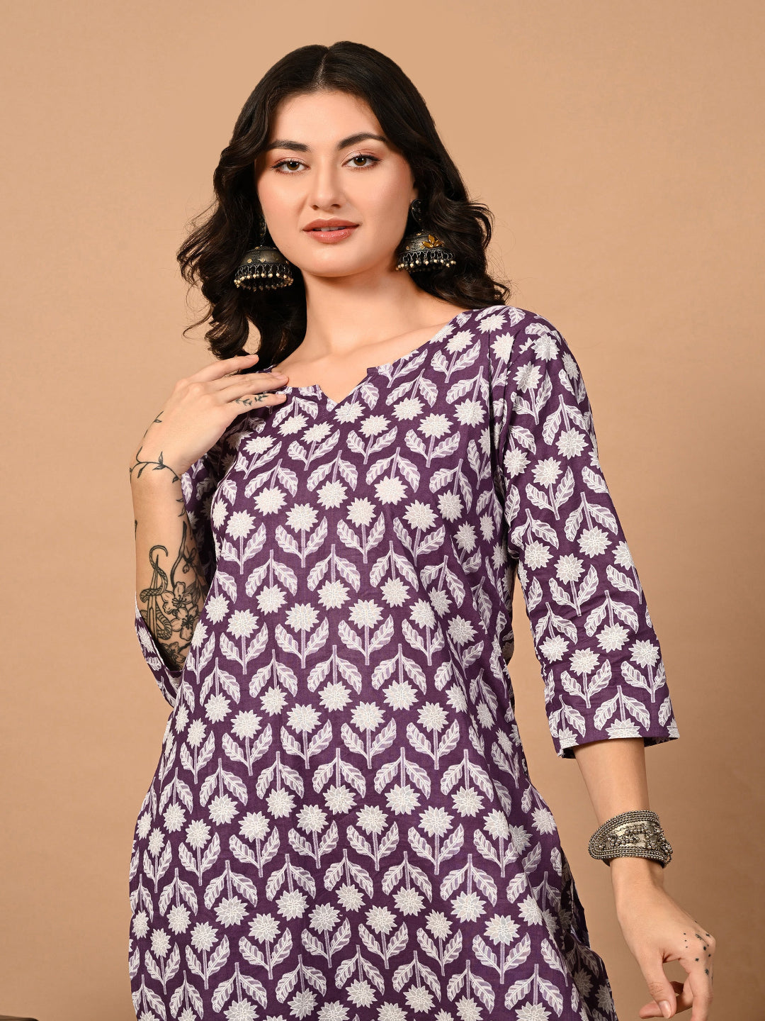 Woman wearing a purple and white patterned dress against a beige background
