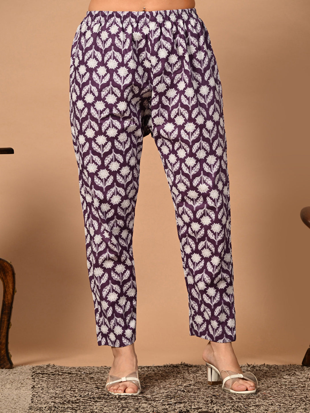 Purple patterned pants worn by a person on a beige background