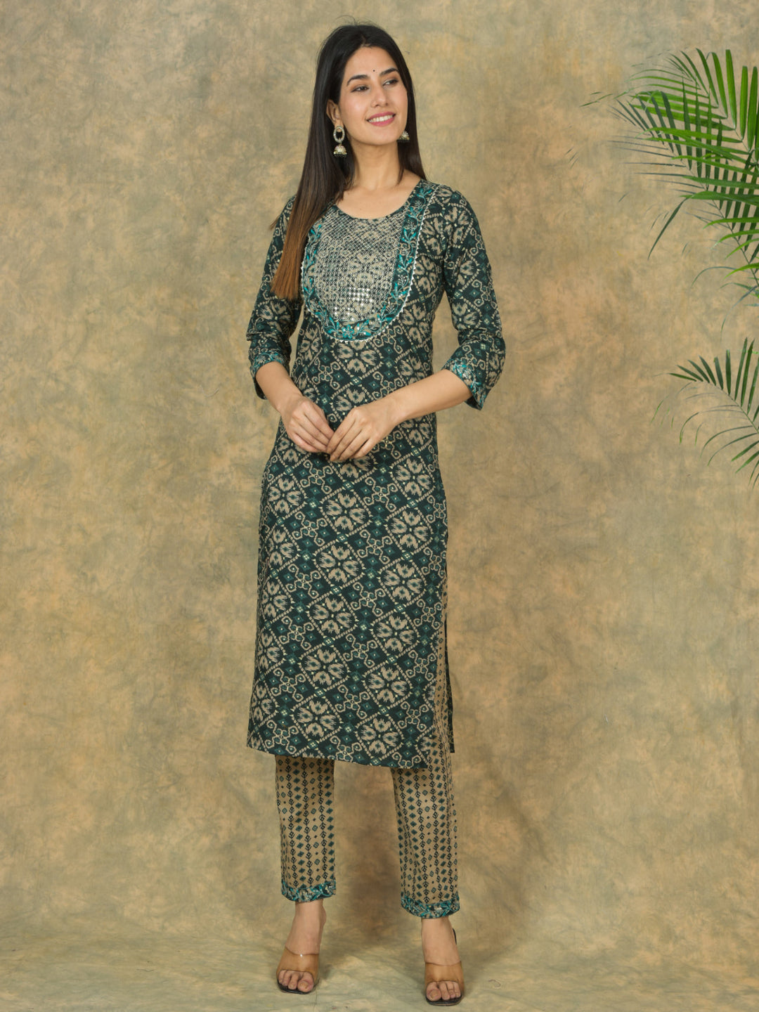 Woman wearing a green patterned kurta with pants against a beige background