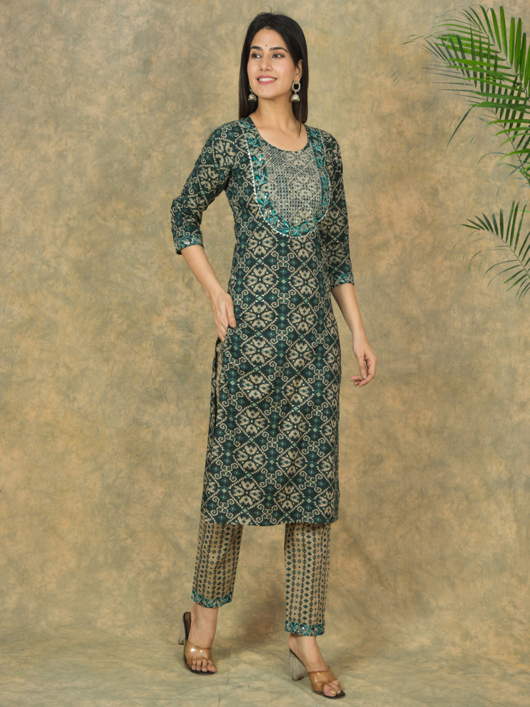 Woman wearing a green patterned kurta with pants against a beige background